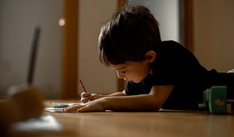 A little boy draws a drawing with colored pencils