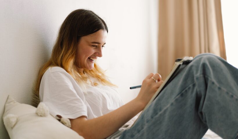 A teenage girl is drawing or doing homework in the bedroom. A teenager studies at home.