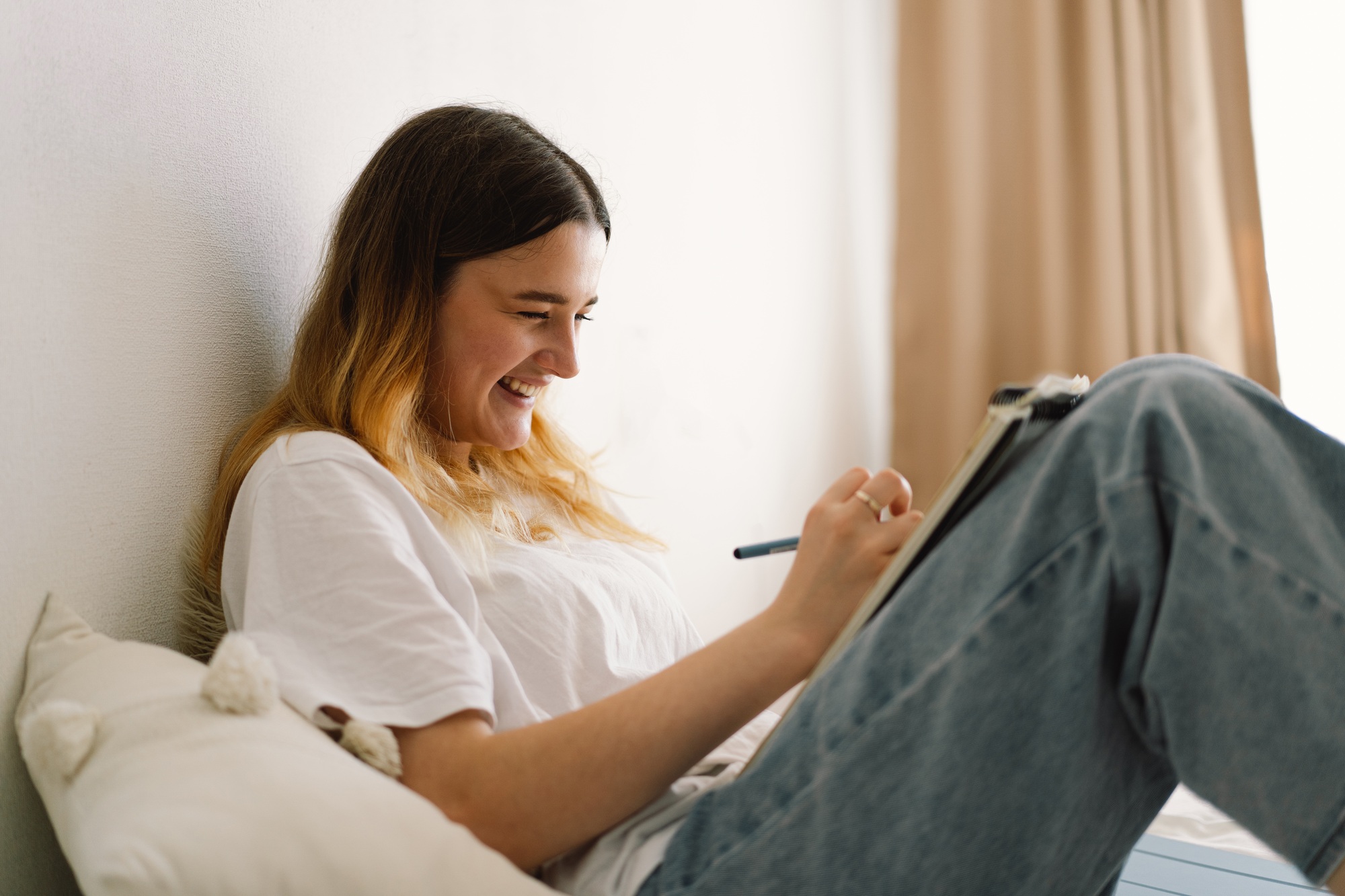 A teenage girl is drawing or doing homework in the bedroom. A teenager studies at home.