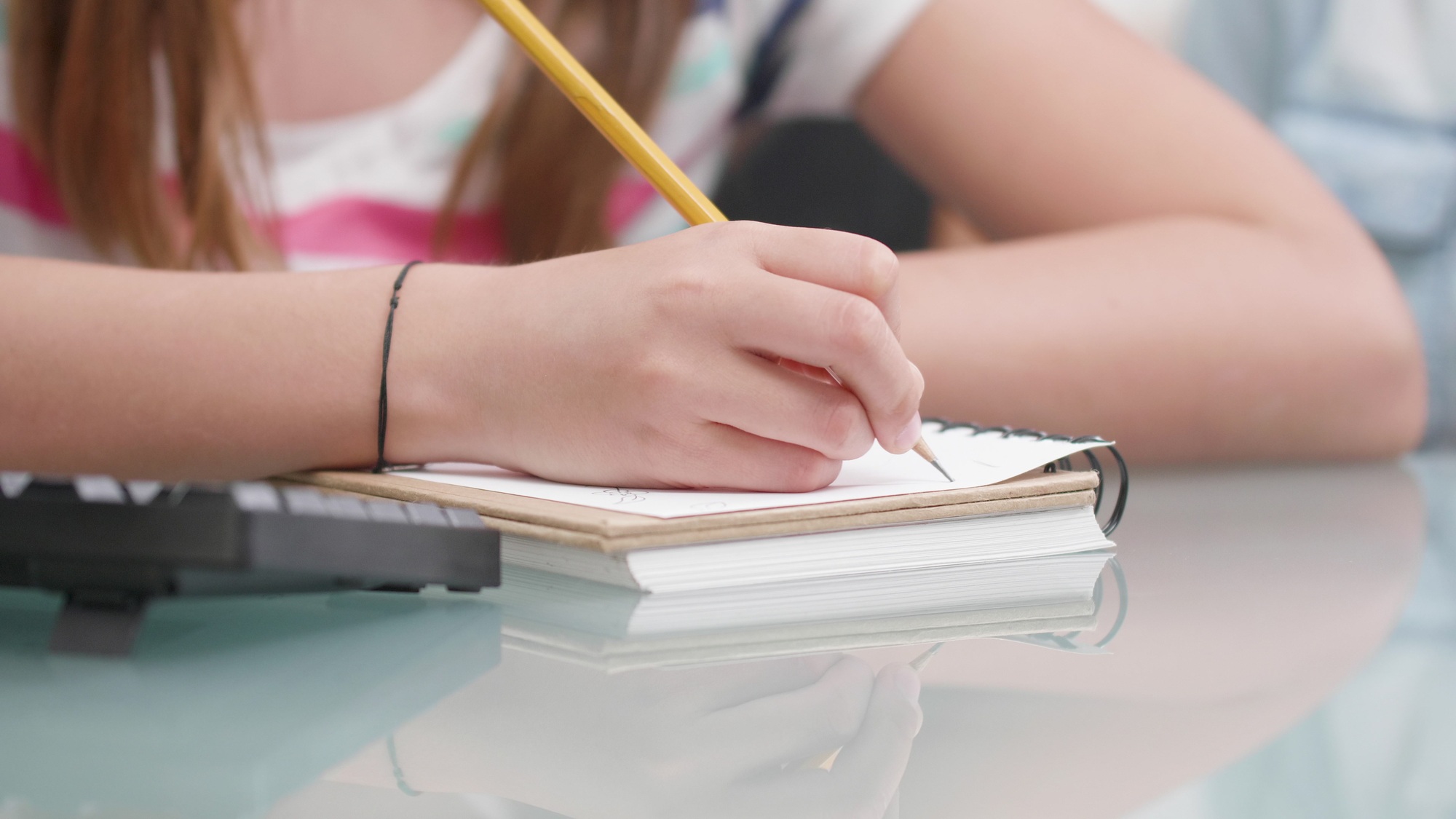 Closeup of young child writing mathematics exercices on notebook