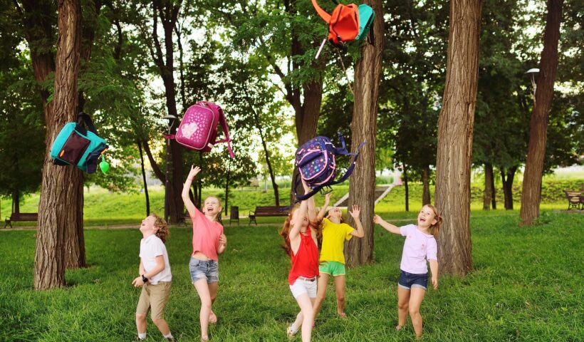 group of school children rejoice at the beginning of the summer holidays, throw up their school