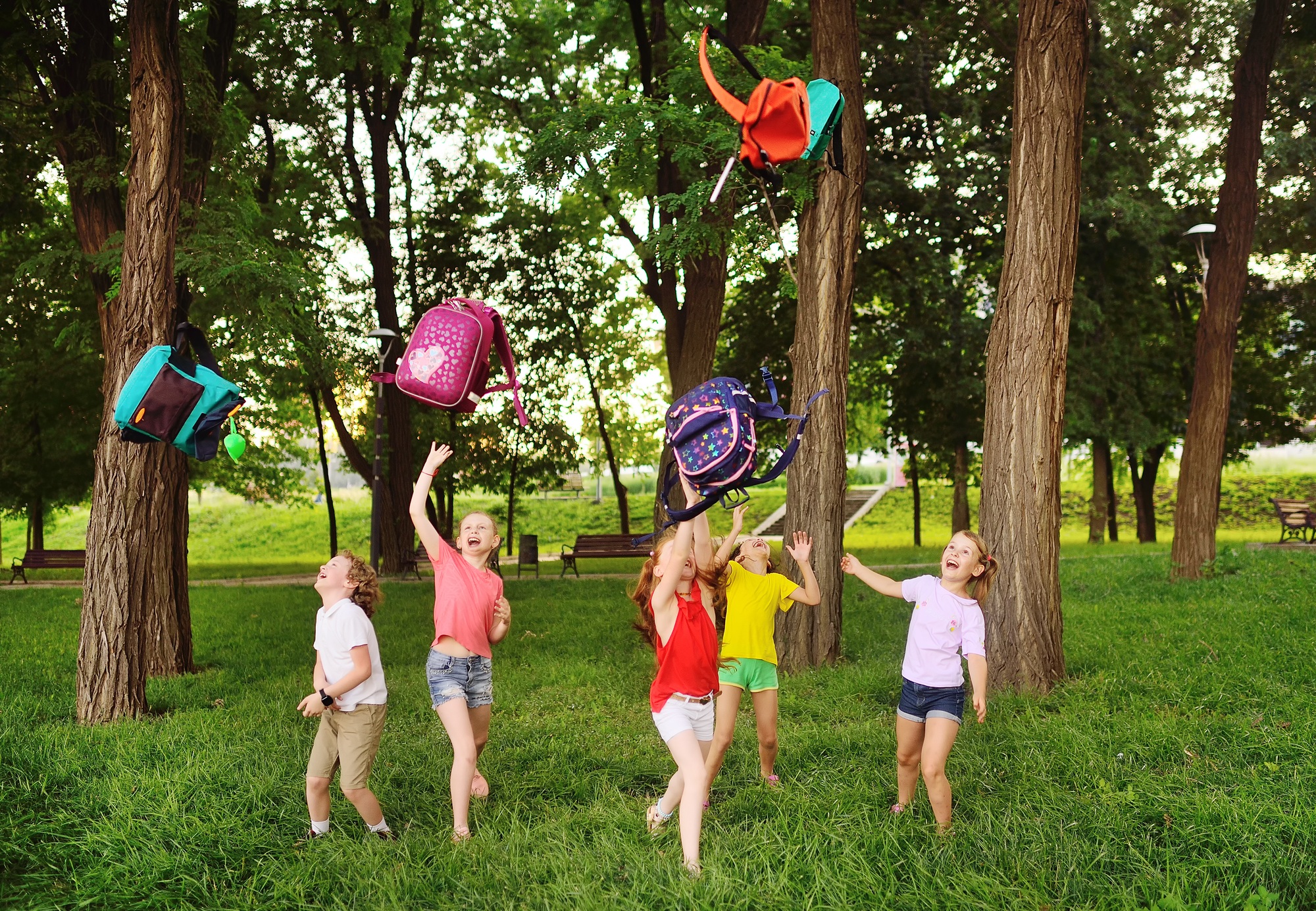 group of school children rejoice at the beginning of the summer holidays, throw up their school