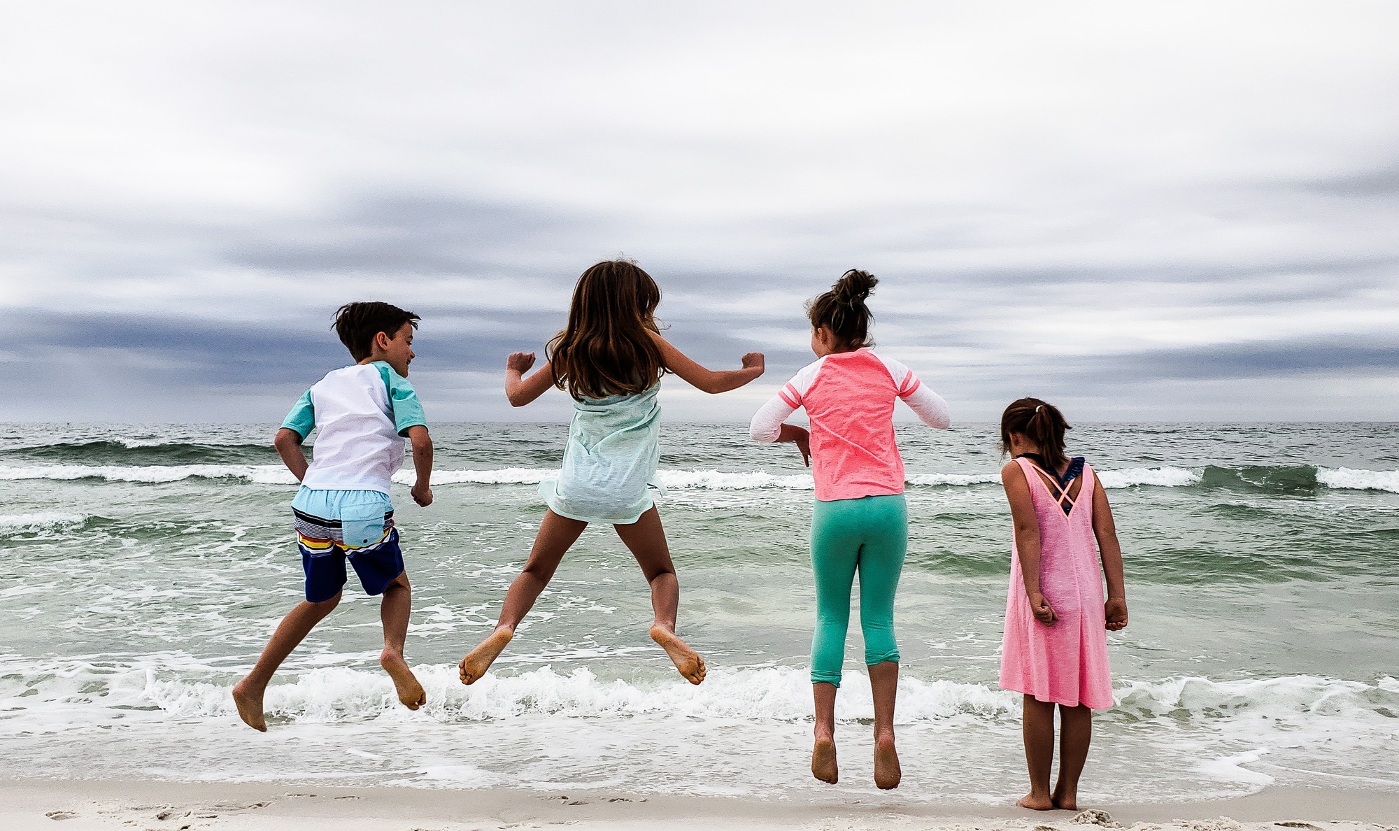 Kids jumping for joy that school is out and they can enjoy their beach vacation.