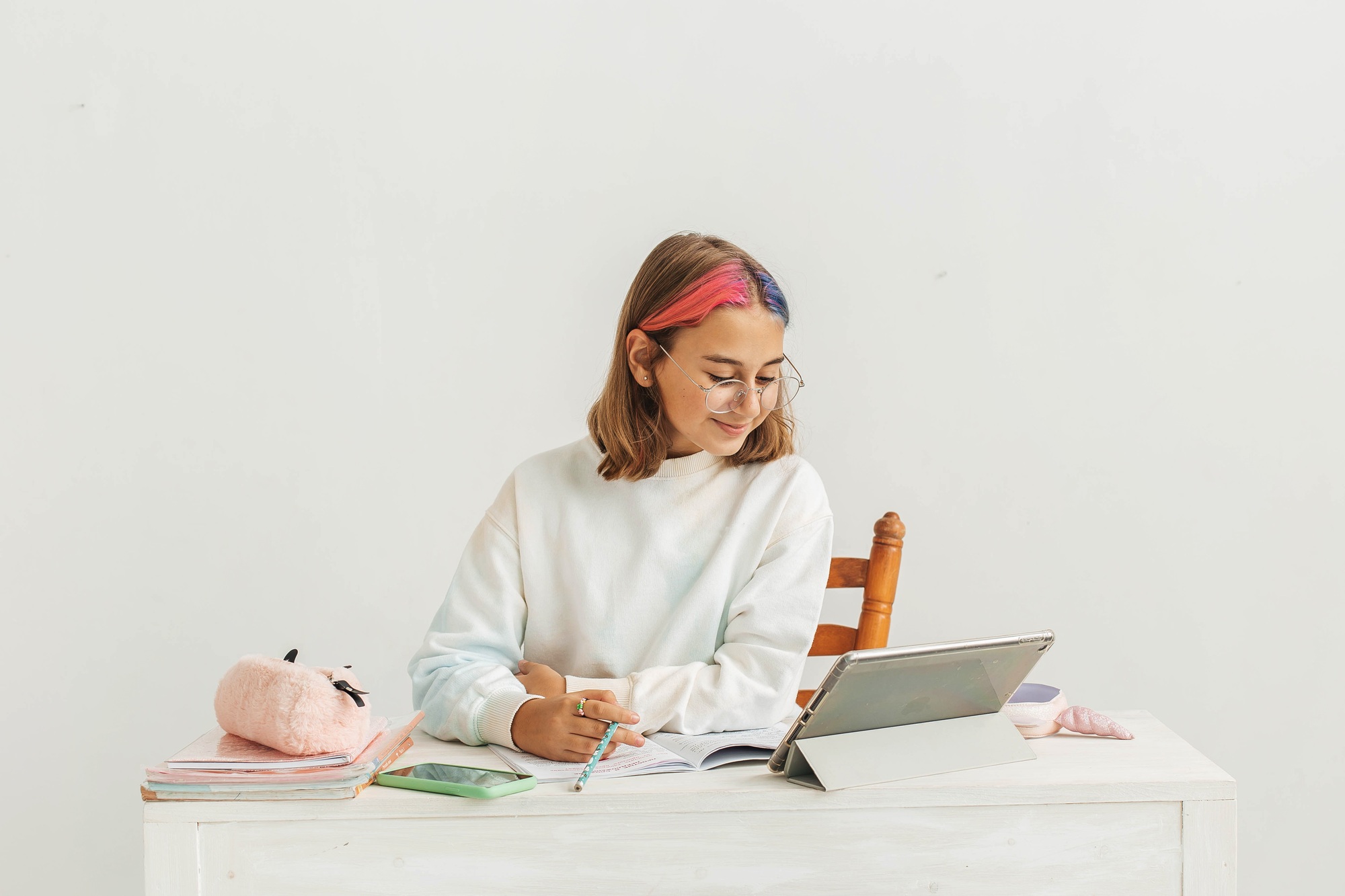 Little teenage girl with multi-colored hair learns online using a laptop.