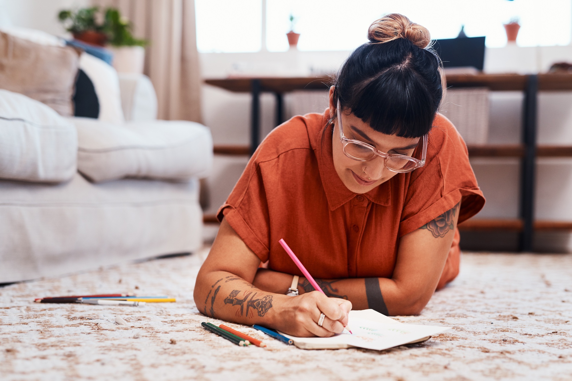 Shot of a young woman using coloring pens while drawing at home