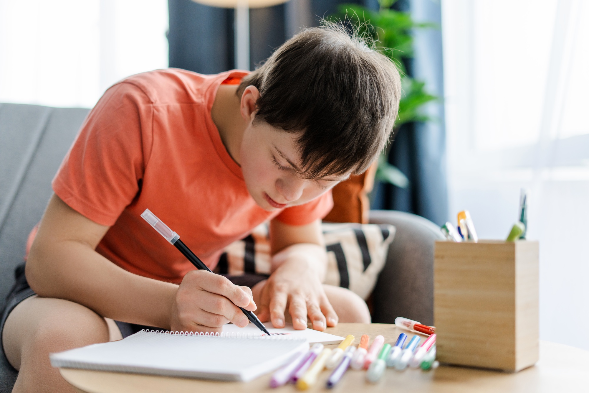 Teen boy with down syndrome drawing with black felt tip pen