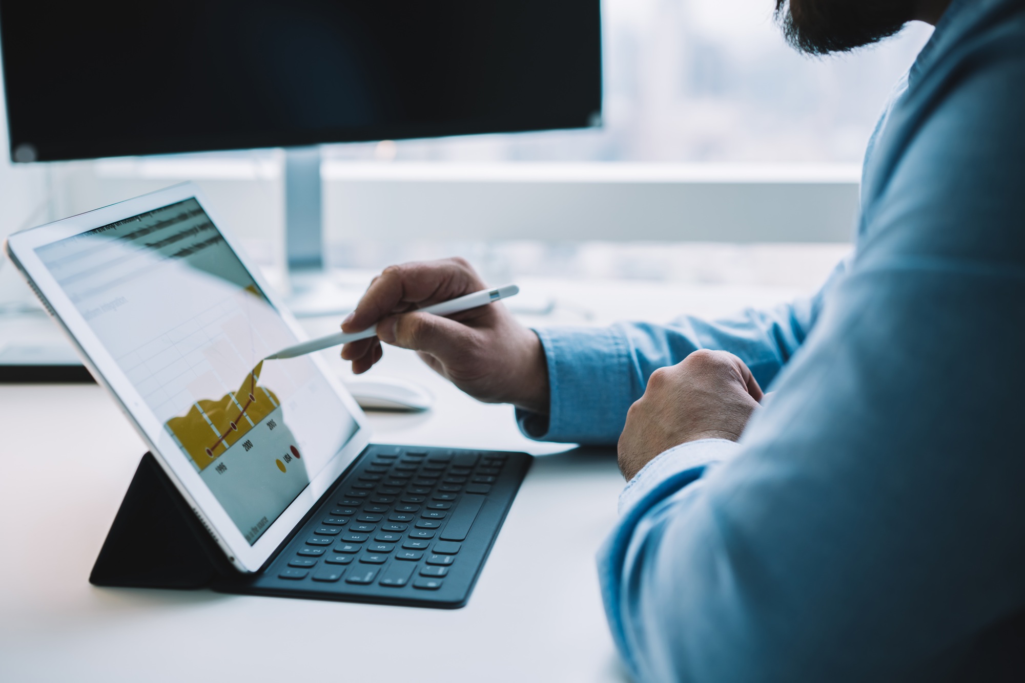 Unrecognizable male employee drawing chart on tablet with stylus
