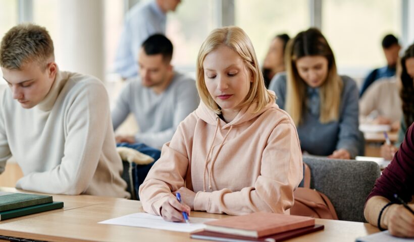 Young woman writing exam in lecture hall at the university.