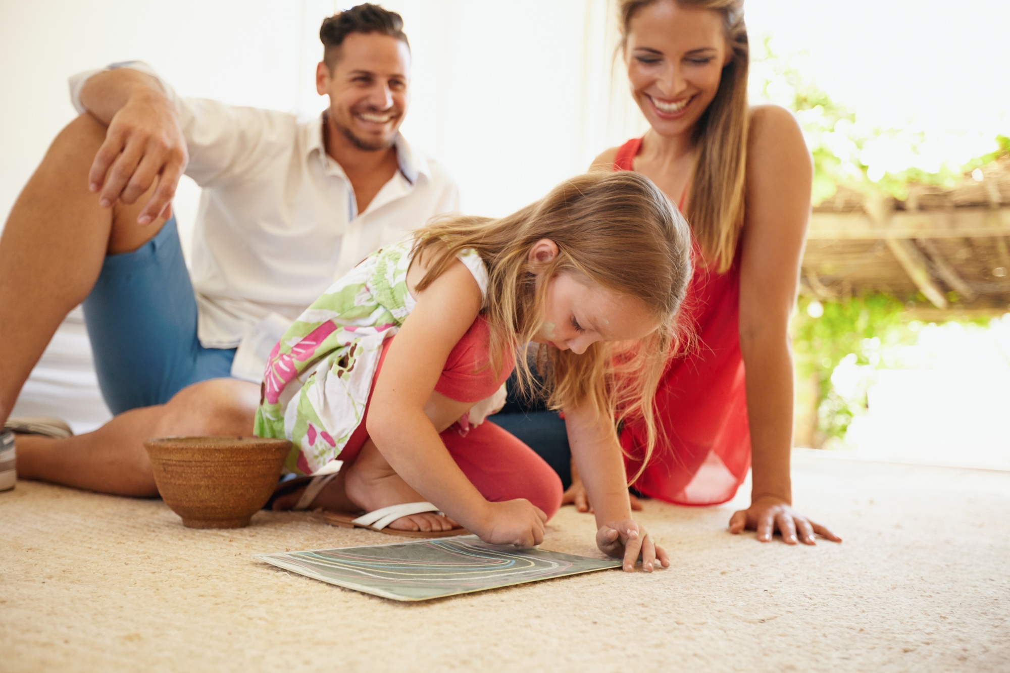 Family sitting on floor with daughter drawing