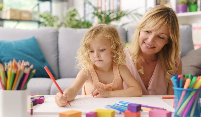 Girl and mother drawing together at home