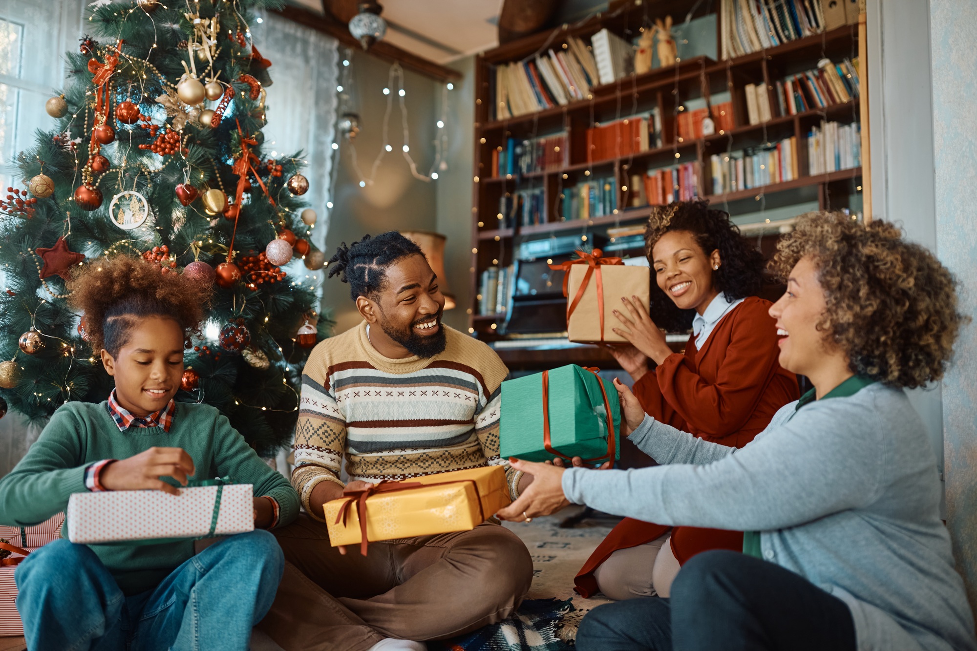 Happy black multi-generation family exchanging gifts at Christmas.