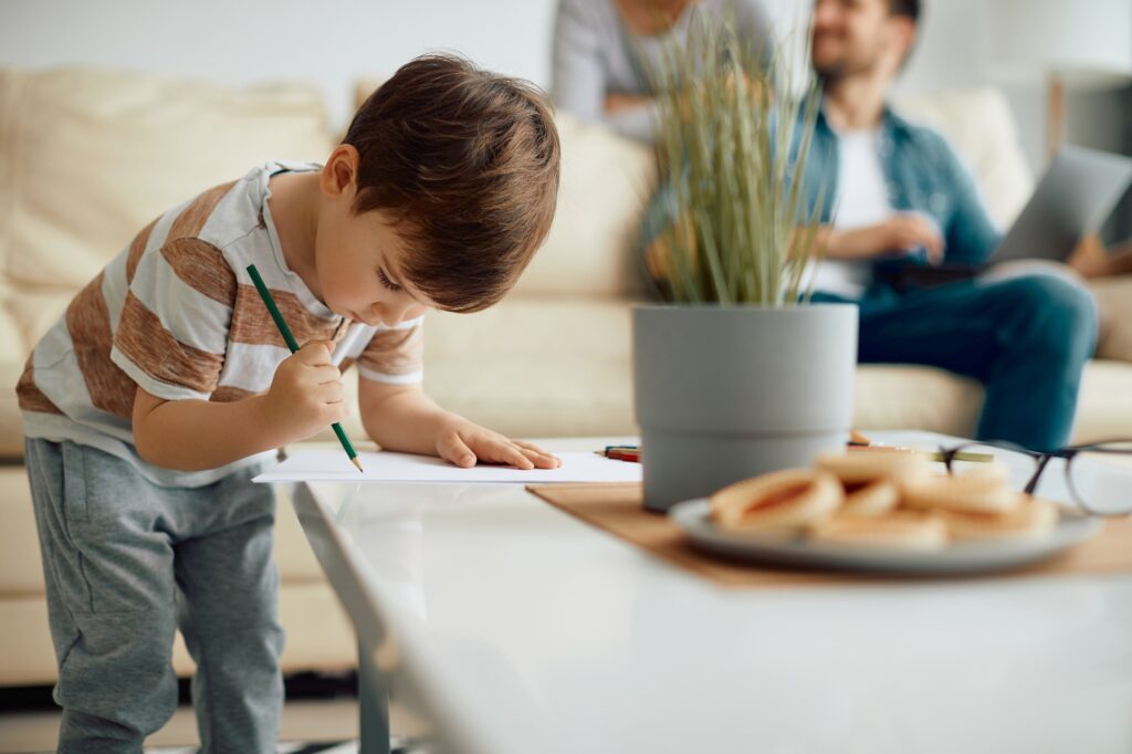 Small boy drawing on the paper at home,