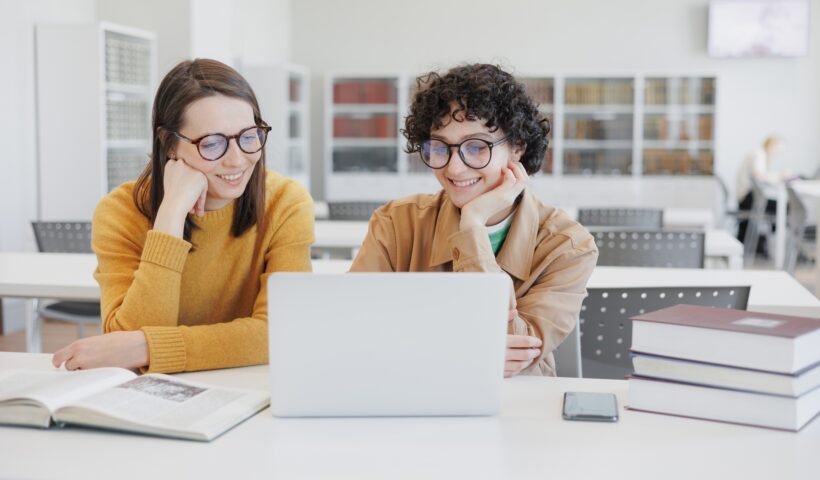two female colleagues work on laptops in coworking office, library. online training webinar