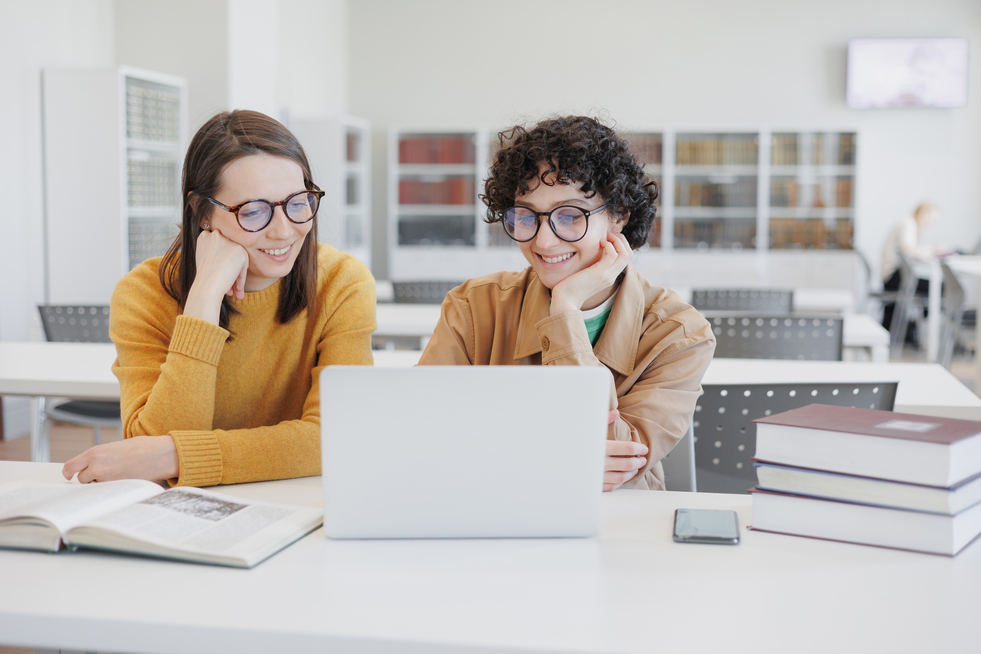 two female colleagues work on laptops in coworking office, library. online training webinar