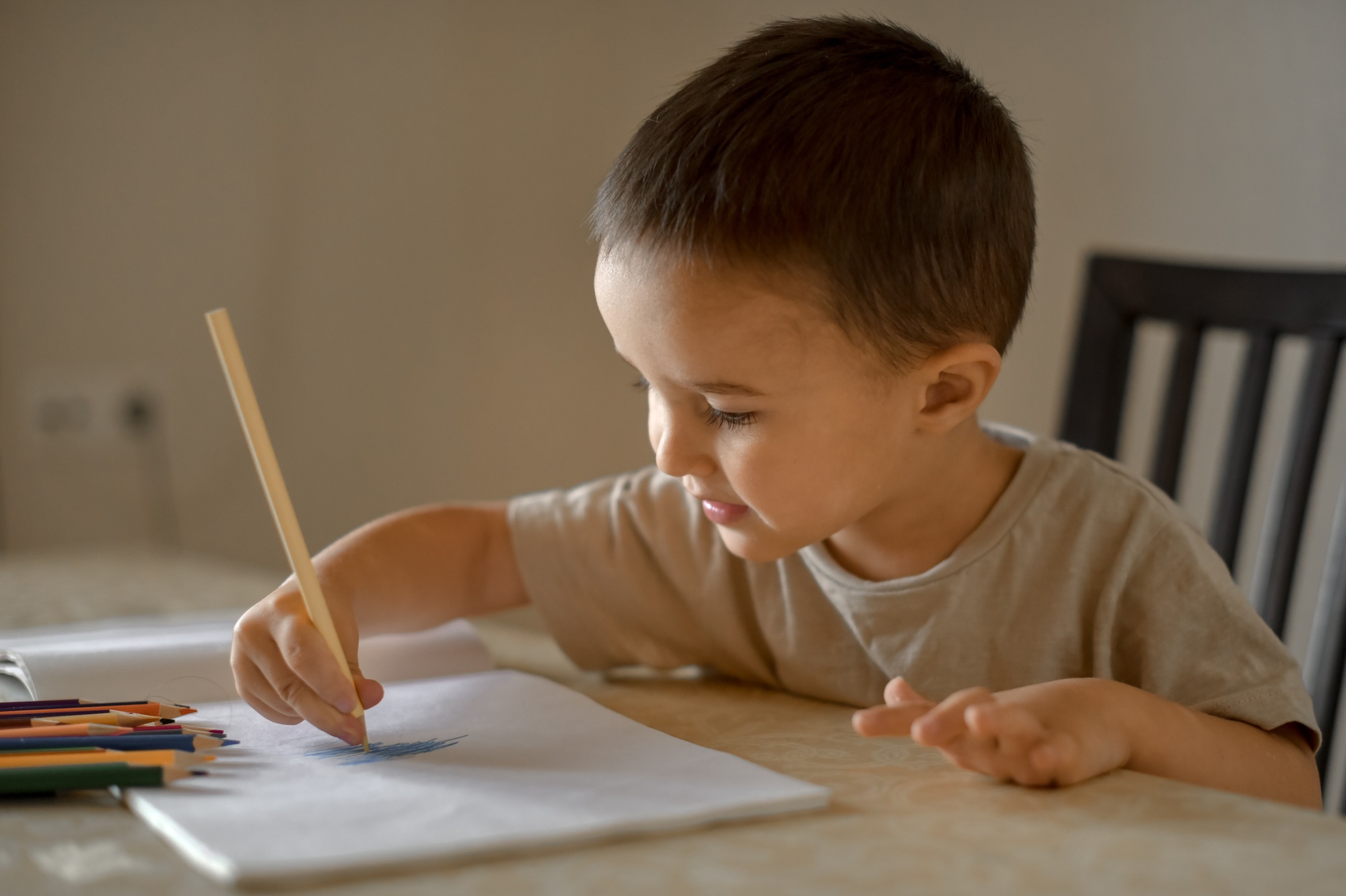 A little boy of three years draws a drawing with colored pencils