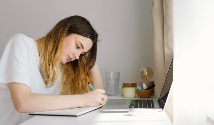 A teenage girl is drawing or doing homework in the bedroom. A teenager studies at home.