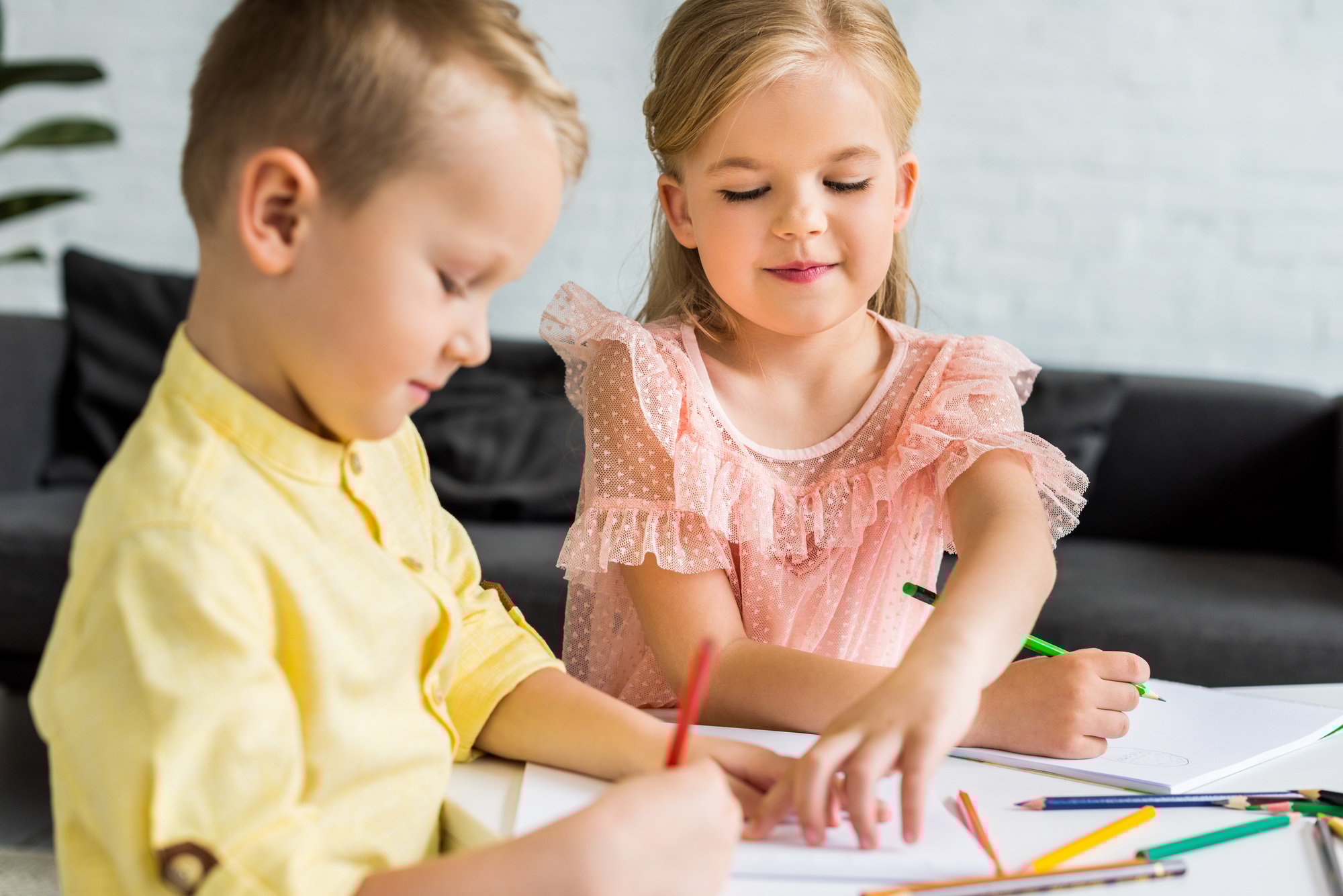 adorable siblings drawing with colored pencils at home
