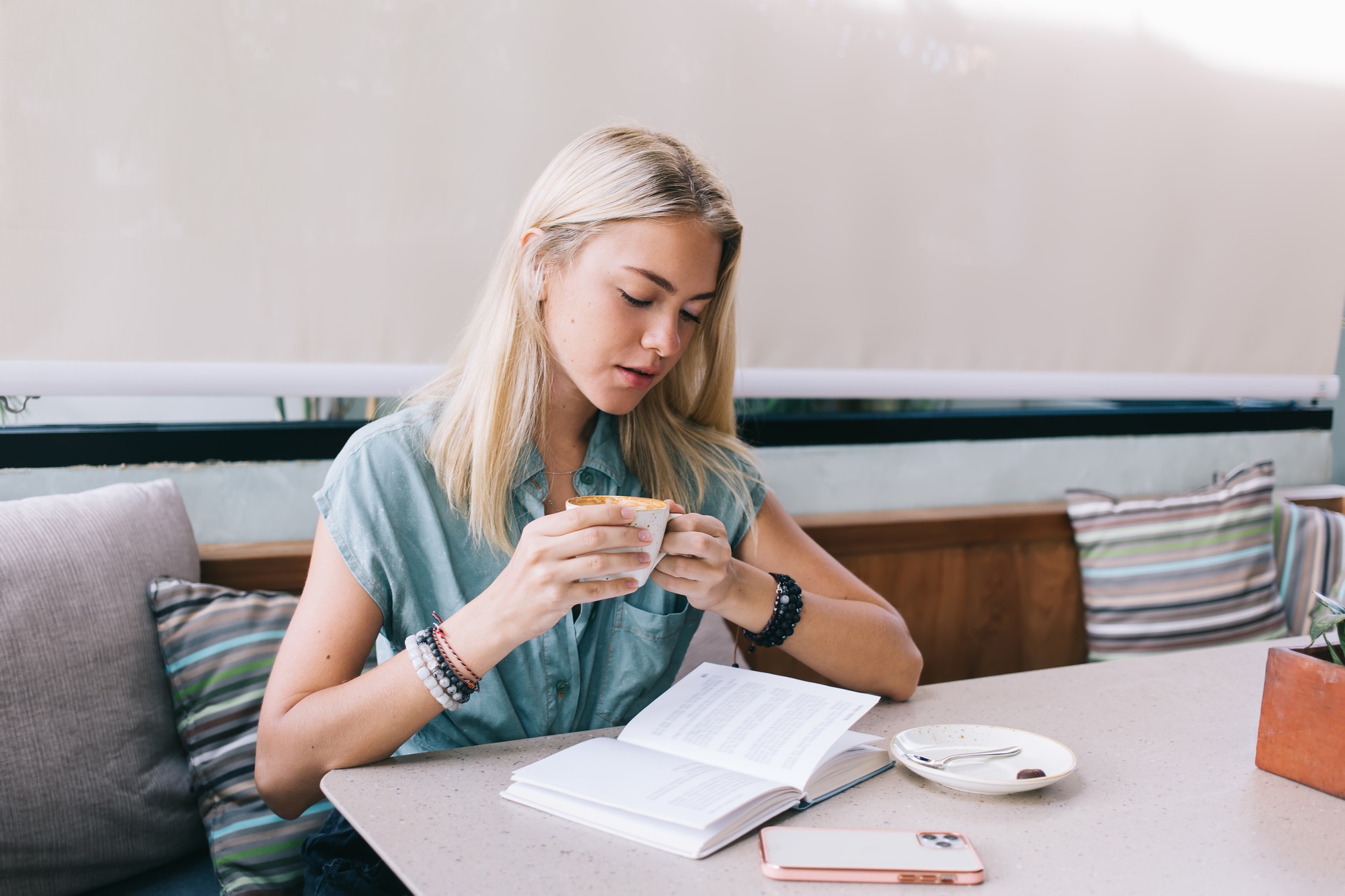 attractive female with tasty cappuccino enjoying free time with poetry best seller or novel