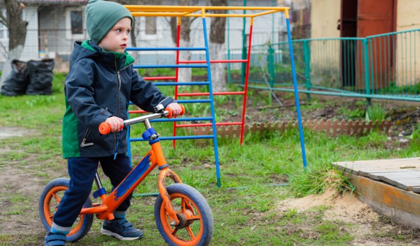 Child rides a balance bike outdoors in the garden