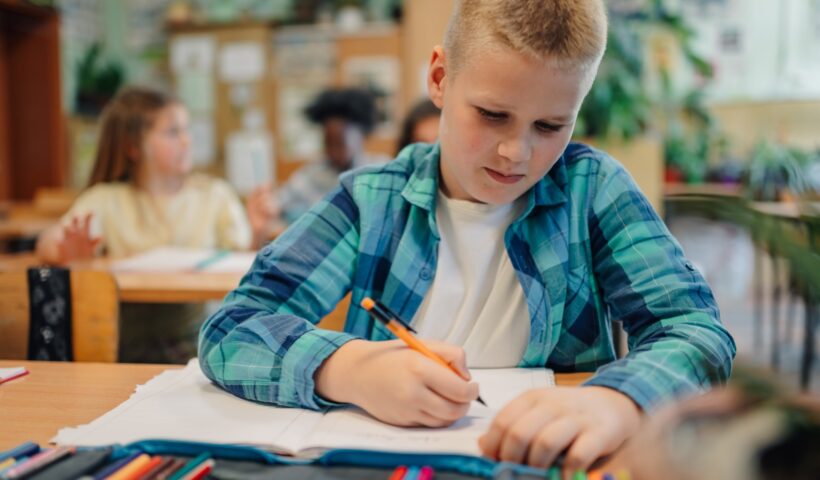 Elementary school student drawing during class with colored pencils