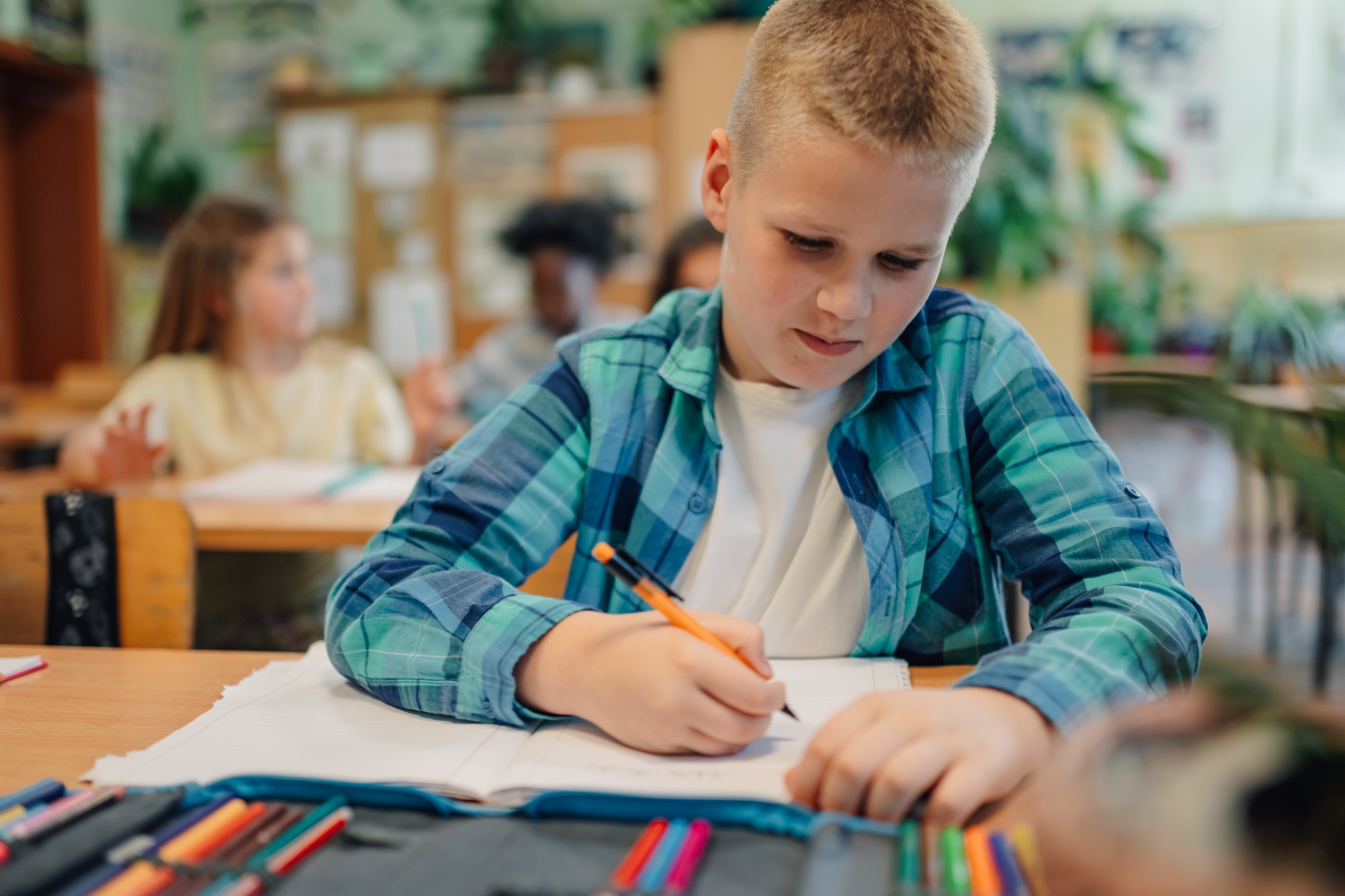 Elementary school student drawing during class with colored pencils