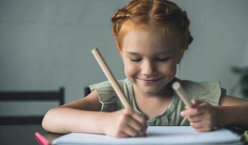 happy beautiful little girl drawing with color pencils