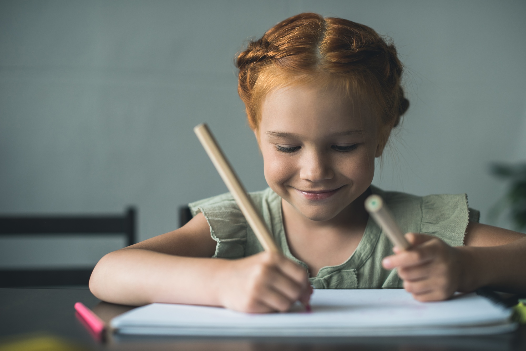 happy beautiful little girl drawing with color pencils