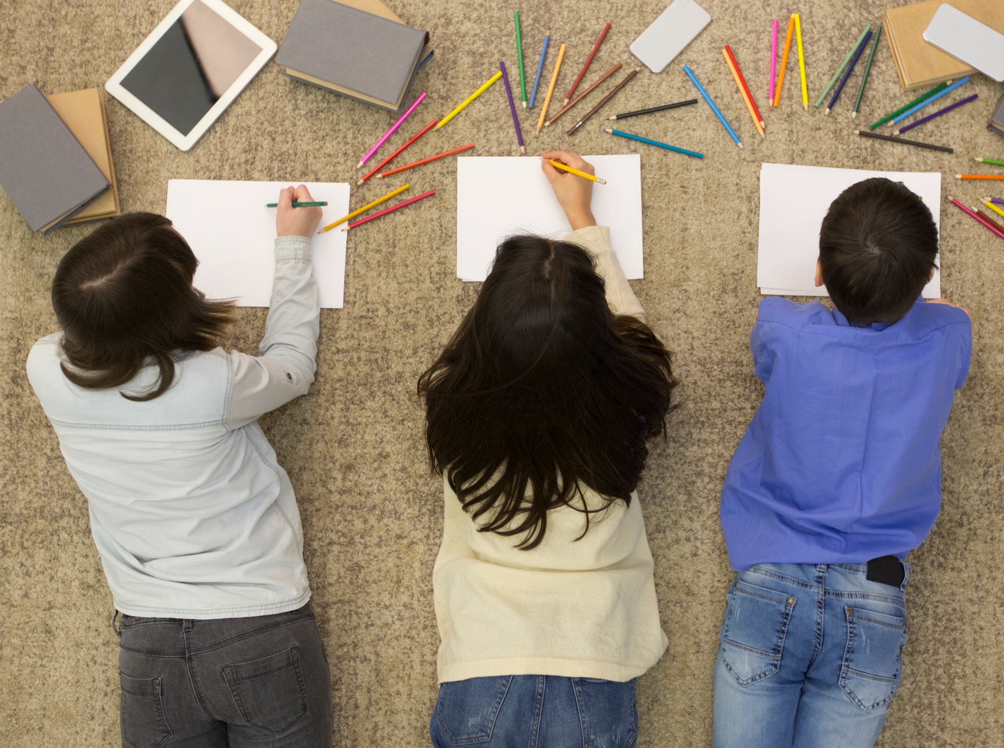 School children drawing with colored pencils on carpet