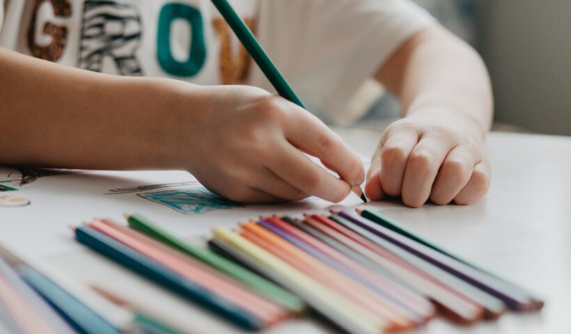 The boy draws with pencils at the kitchen, closeup