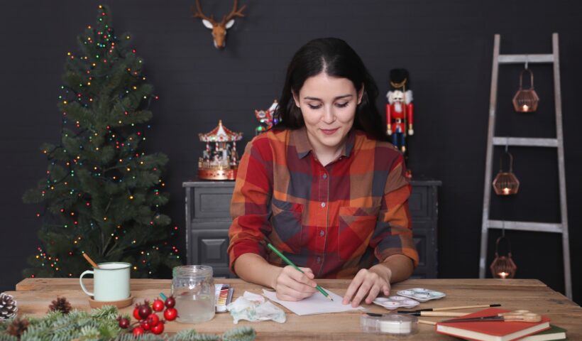 Young woman drawing Christmas card with pencil