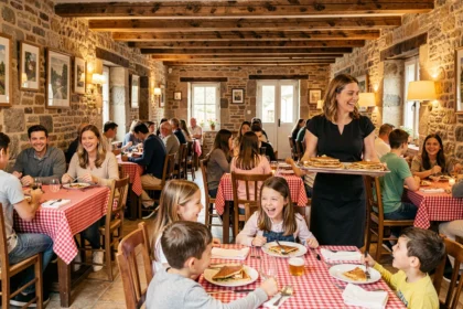 Vue d'ensemble d'un restaurant familial breton chaleureux avec parents et enfants attablés dans une salle aux pierres apparentes